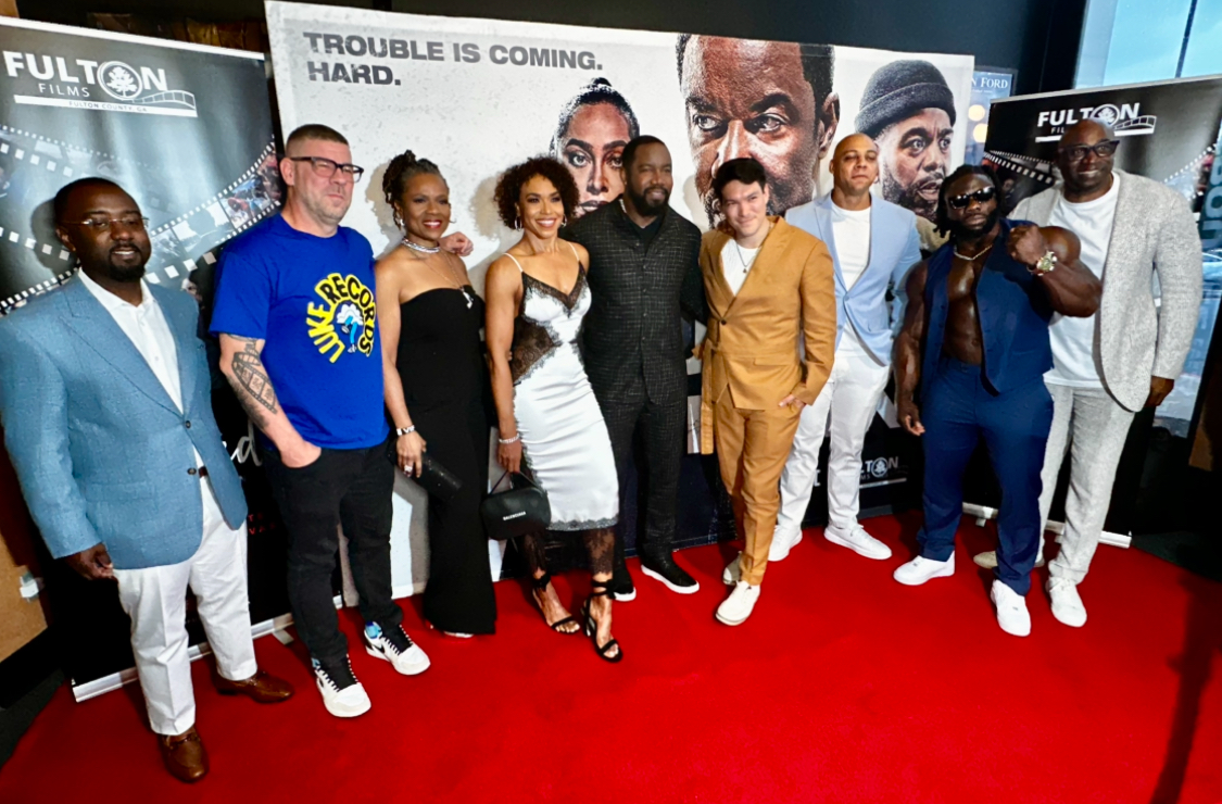 Cast and crew posing on the red carpet at a movie premiere.